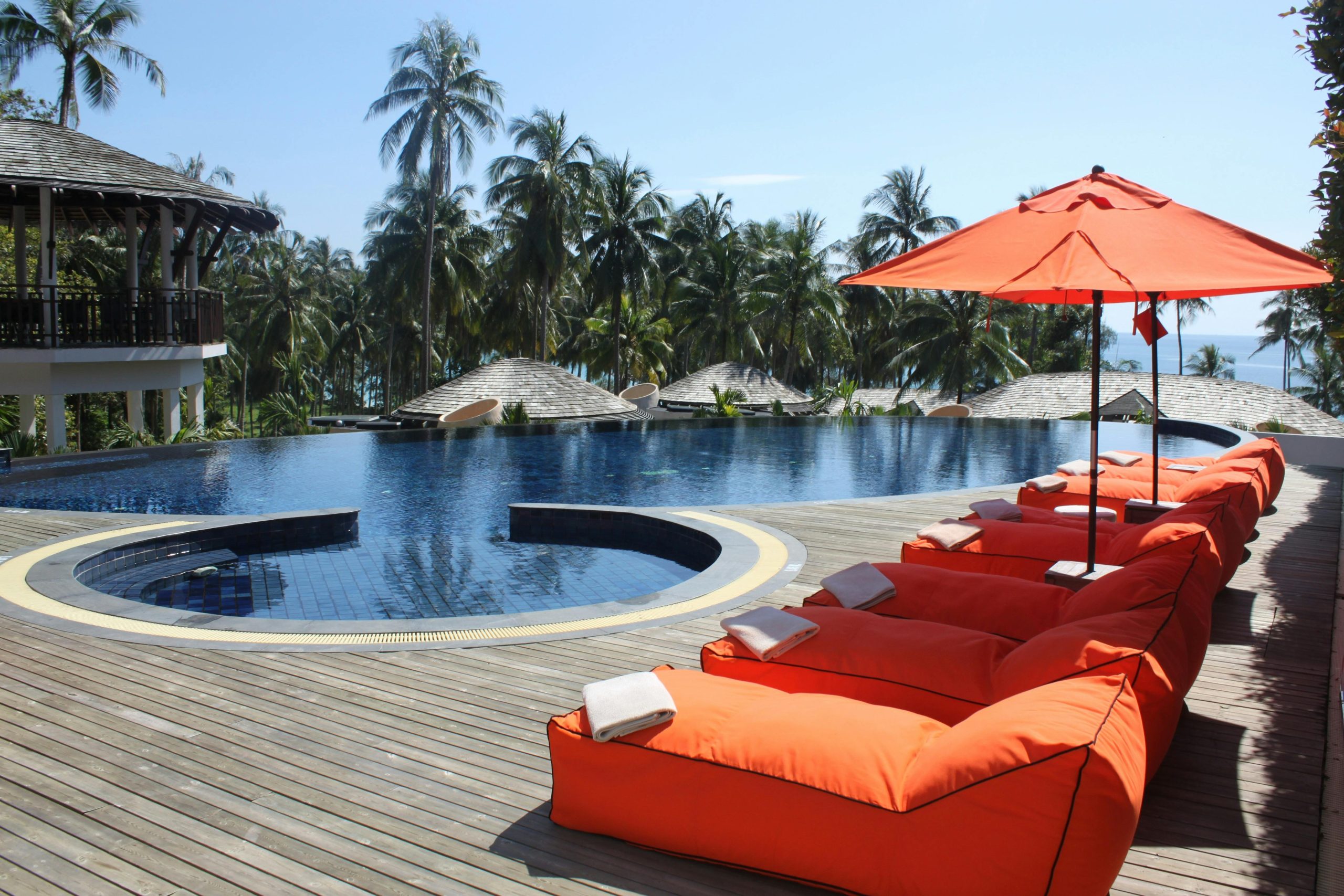 Relax at a tropical resort with sun loungers and palm trees by the pool.