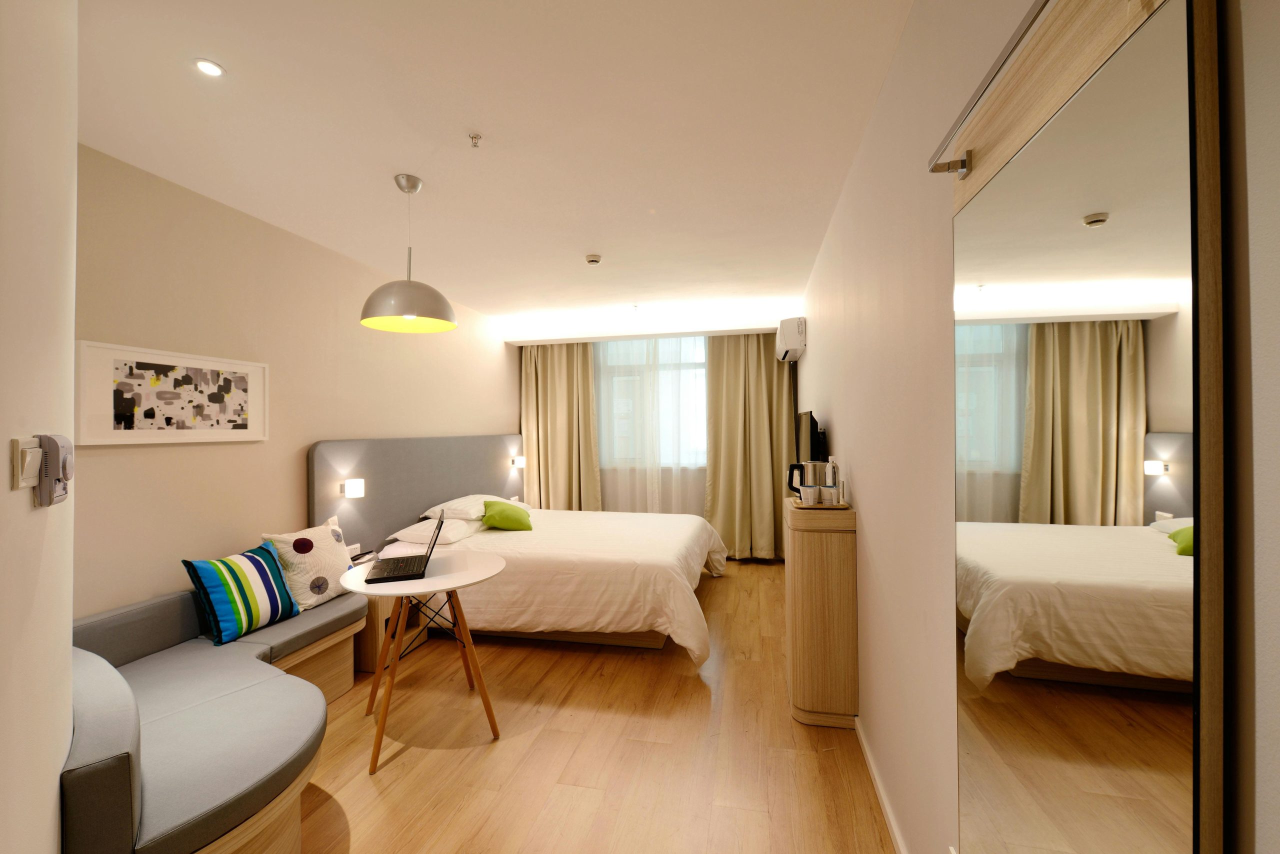 Spacious modern hotel room featuring cozy decor and neutral tones with natural light.