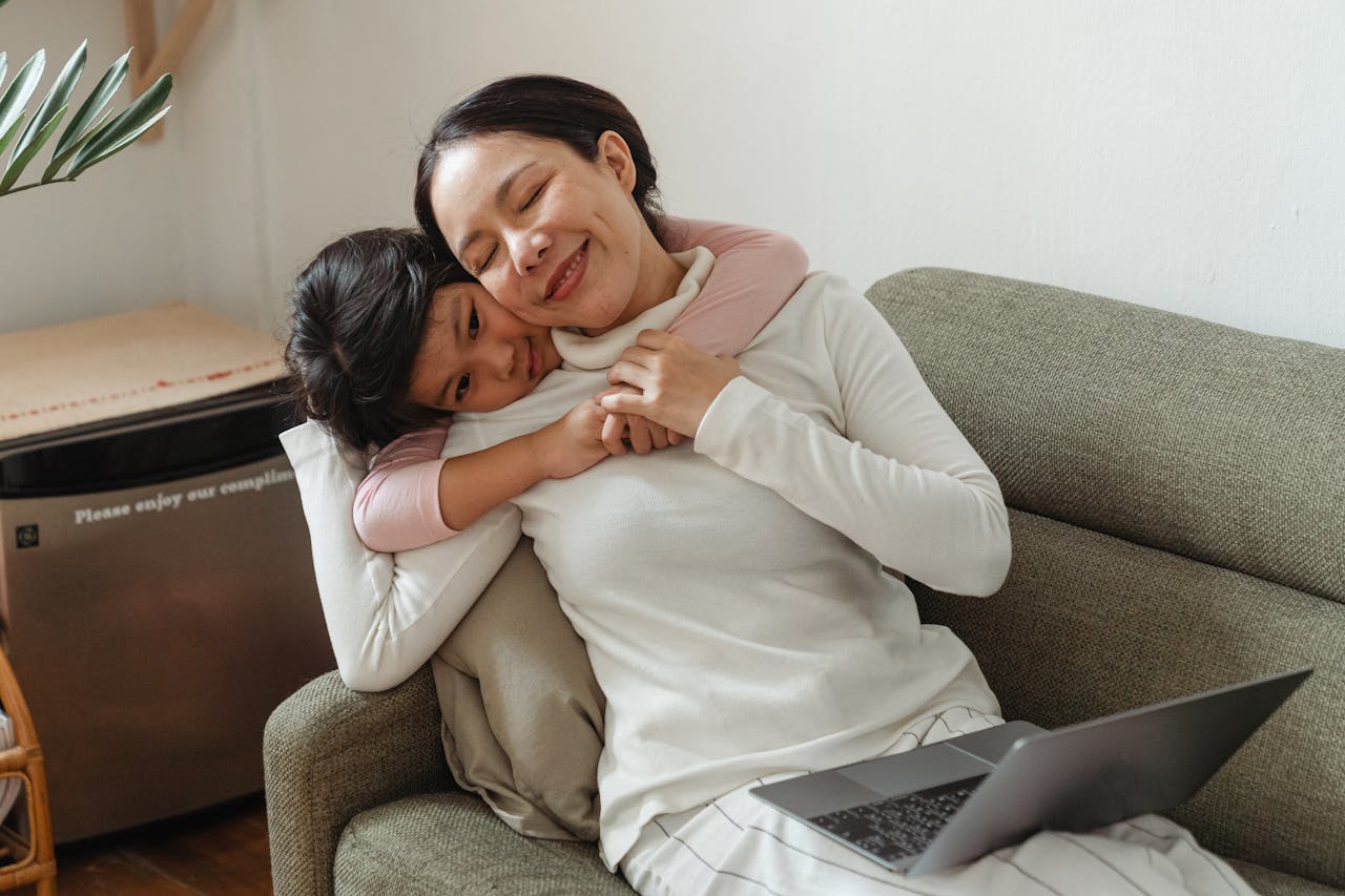 services-10 A mother and daughter share a loving embrace on a sofa, enjoying quality time together indoors.