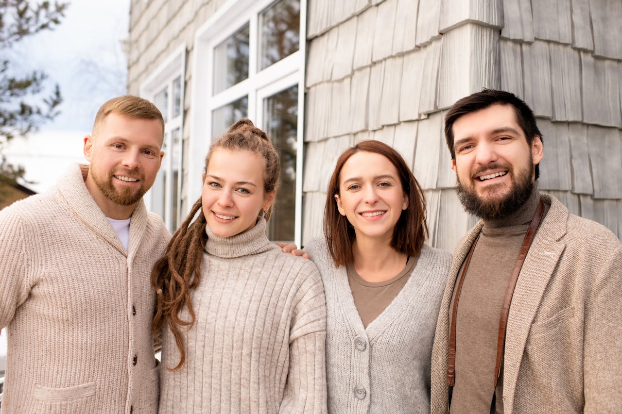 A group of happy friends smiling and posing together outdoors in cozy sweaters.