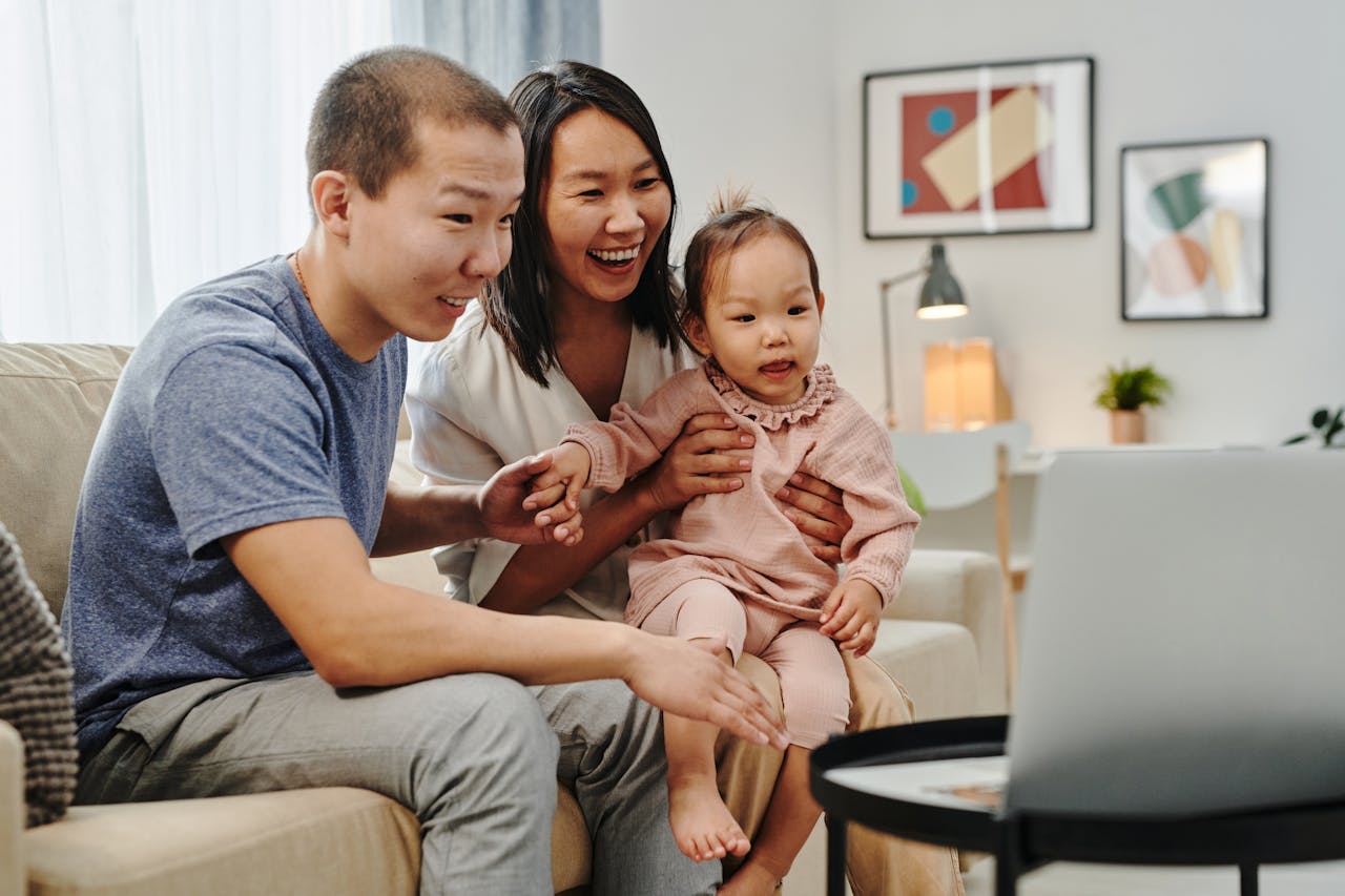 gallery-02 Smiling Asian family sitting on couch having a video call. Perfect for technology and lifestyle themes.