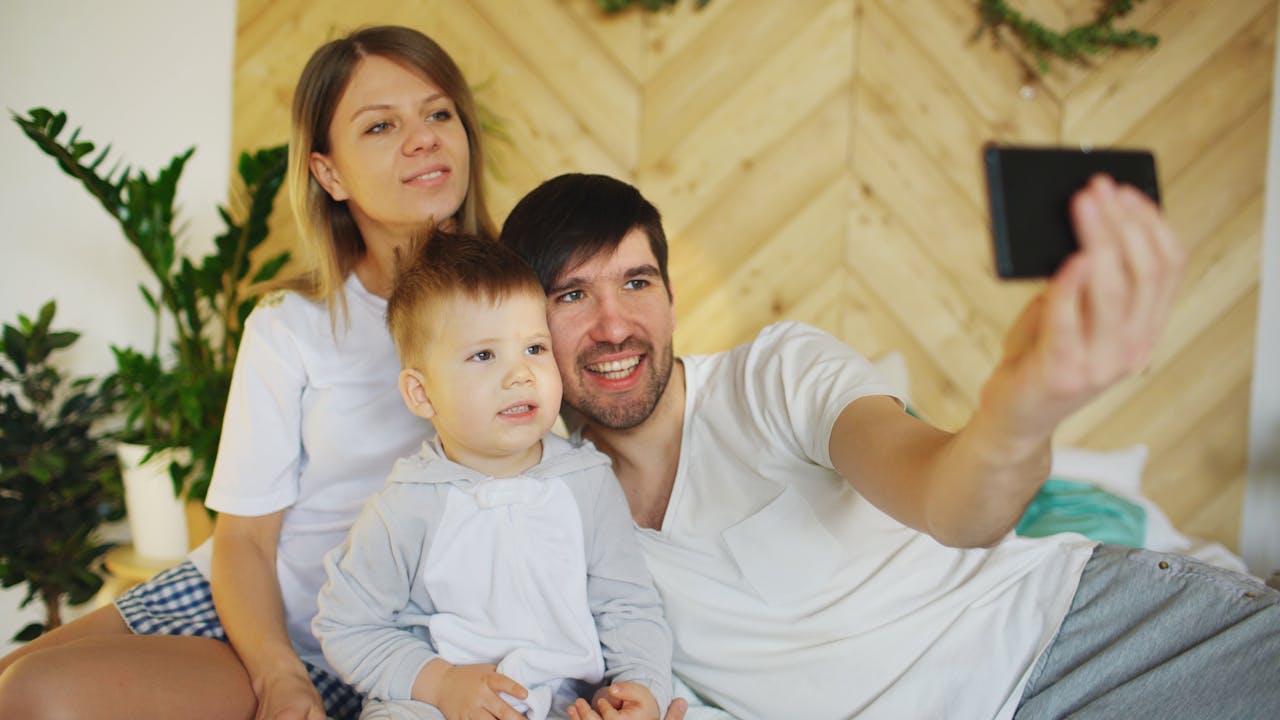 A joyful family of three enjoys a selfie moment indoors, capturing happy memories.