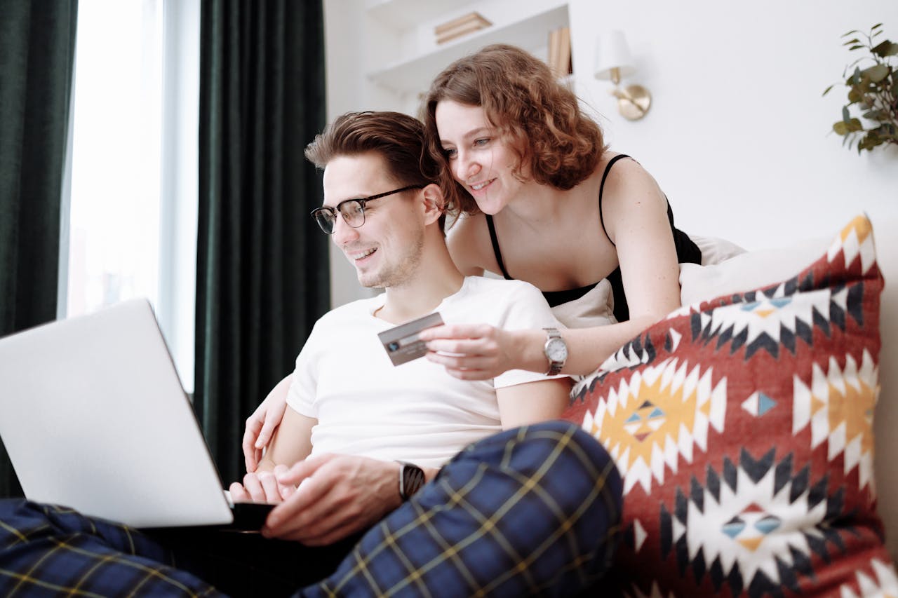 Happy couple using laptop for online shopping while sitting together at home.