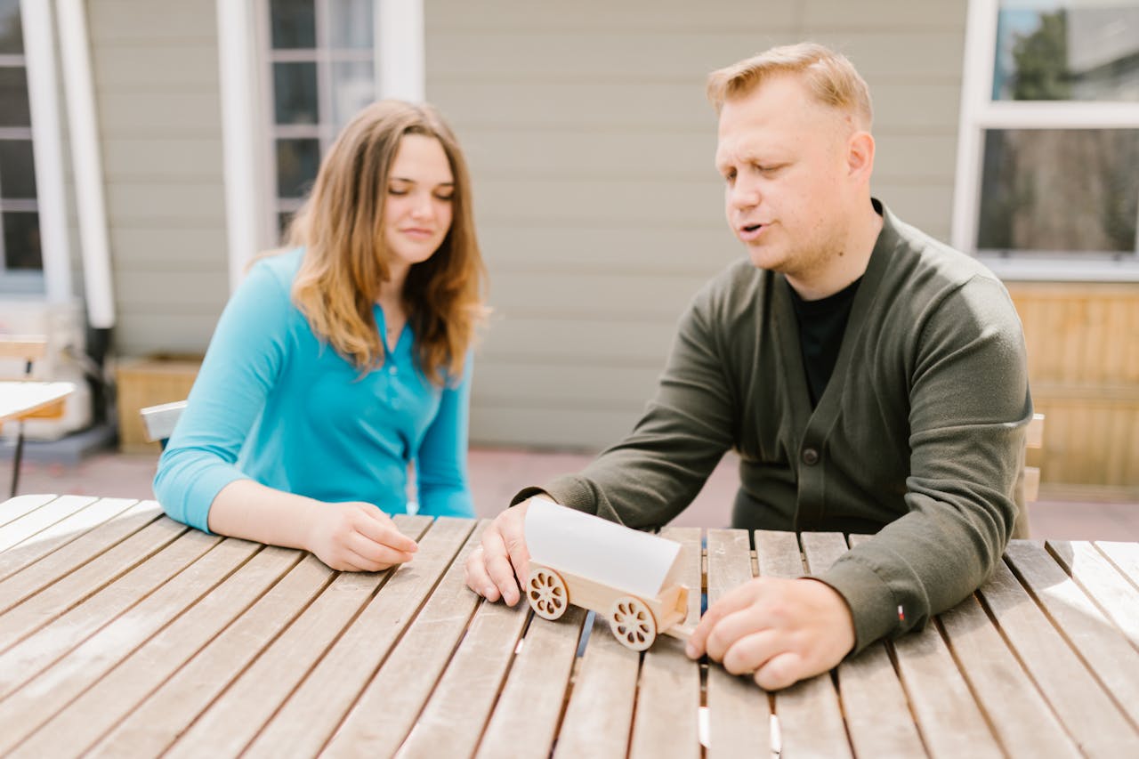 Father and daughter enjoying quality time outside with a handcrafted wooden toy.